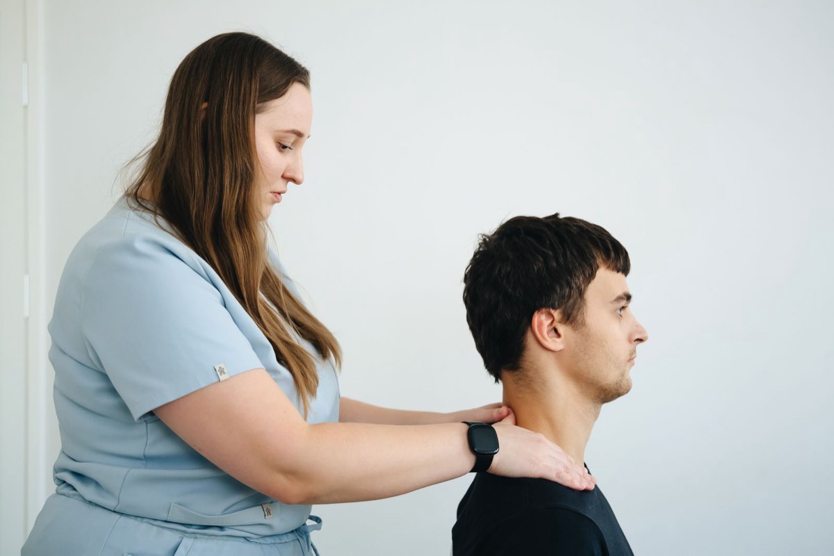 Physiotherapeutin behandelt den Nacken eines Patienten